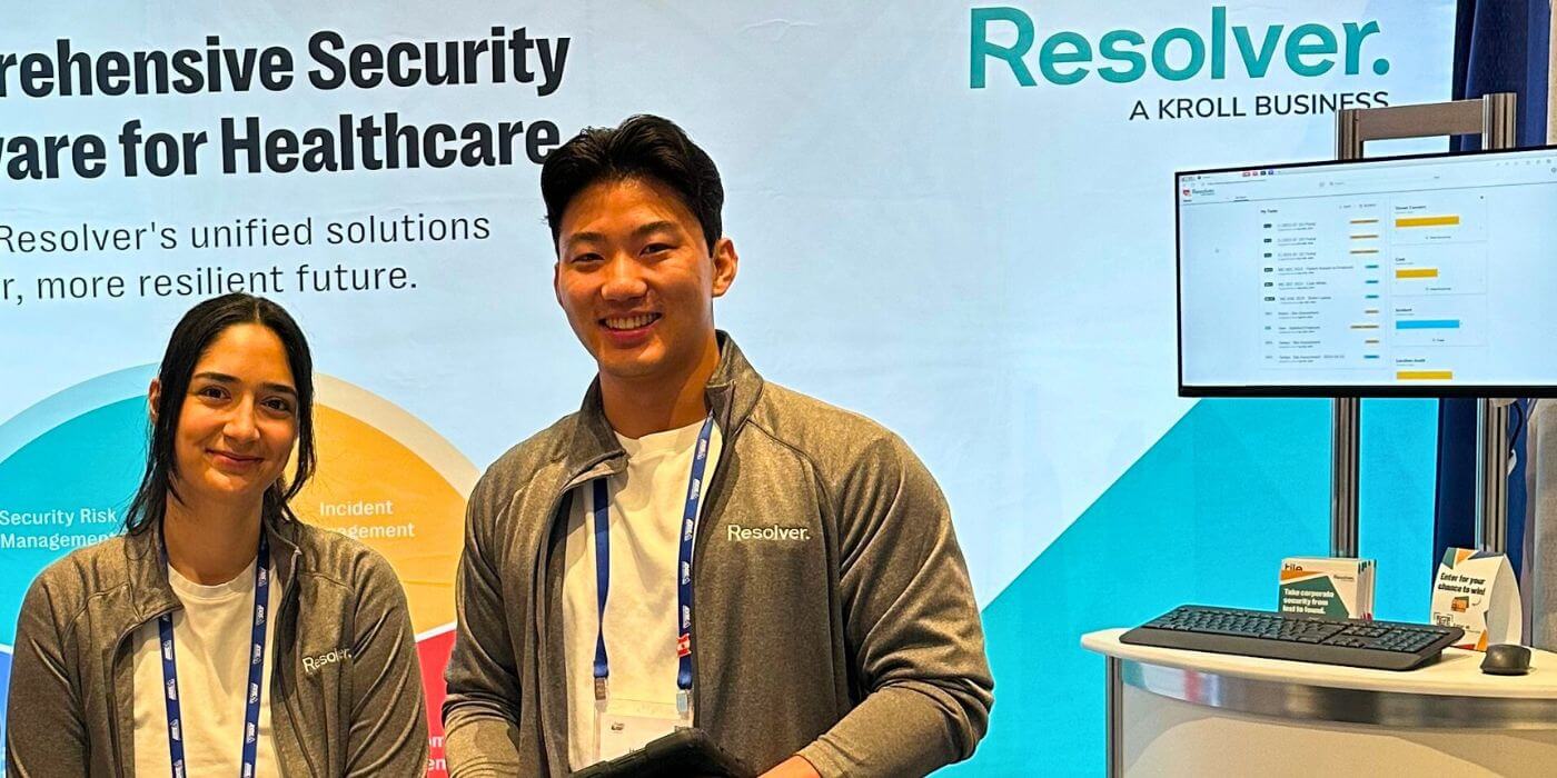 Resolver representatives posing at a booth for resolver's healthcare security software at the iahss 2024 conference. The backdrop highlights the software's key features, and the display includes a section labeled "common challenges faced in hospitals," focusing on issues like vulnerable patients, security regulations, and workplace violence.
