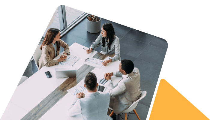 A team of professionals having a meeting in a modern office space. A woman sits at the head of the table engaging with her colleagues.