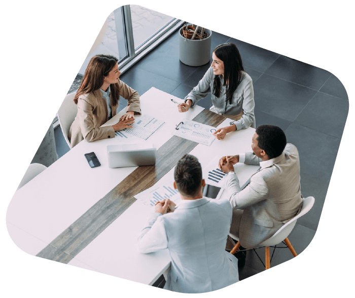 A team of professionals having a meeting in a modern office space. A woman sits at the head of the table engaging with her colleagues.