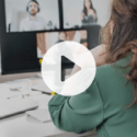Ai and regulatory compliance: the true cost of compliance delays 4 Rear view of a woman with long brown hair clipped back, seated at a white desk in a bright home office. In front of her is a large monitor displaying four people in a video call grid. An open silver laptop sits to the left of the monitor, and she rests her hand near her neck while looking at the screen representing resolver's webinar, "operationalizing ai in grc"